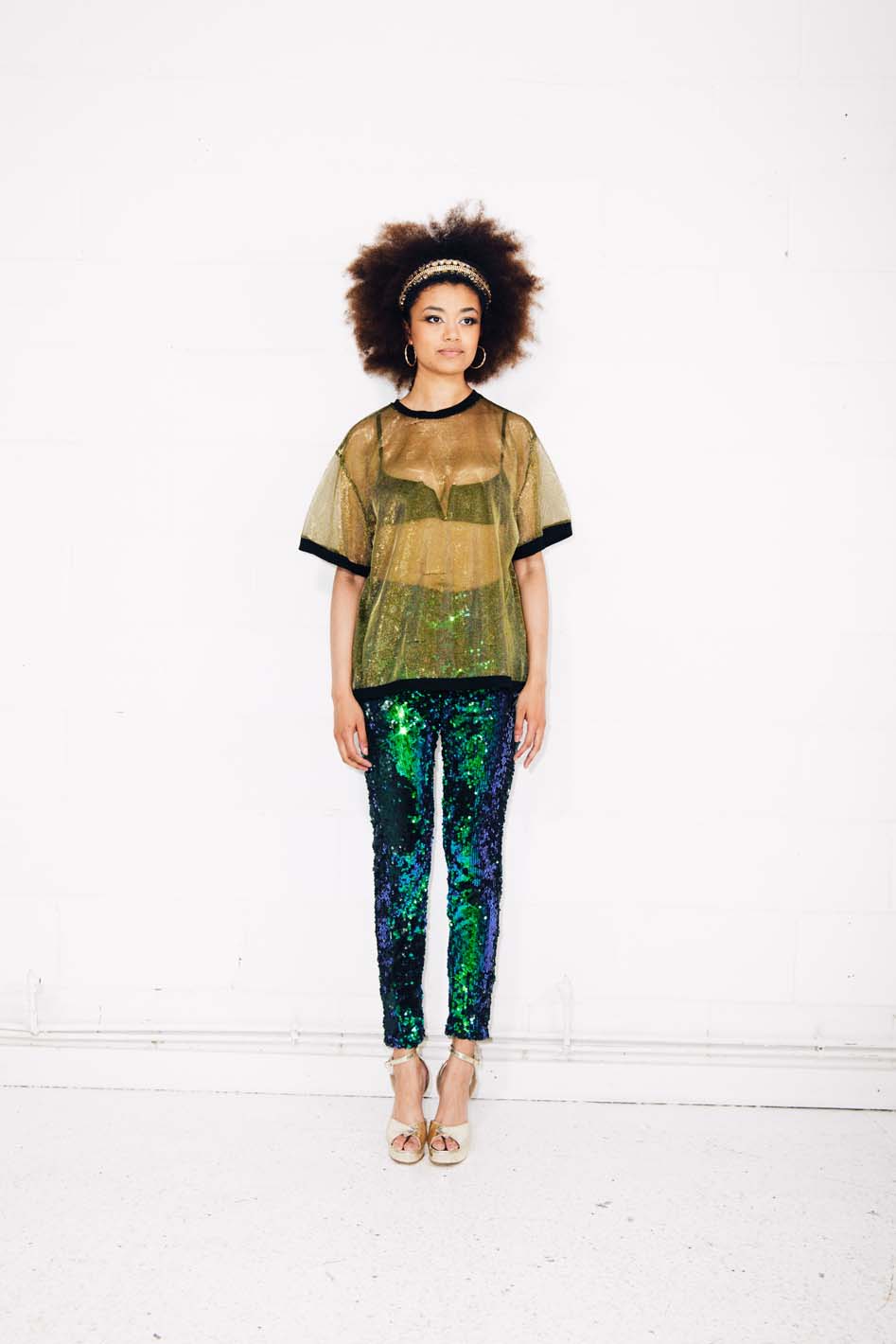 Woman wearing green sequin pants and gold sheer t-shirt at festival
