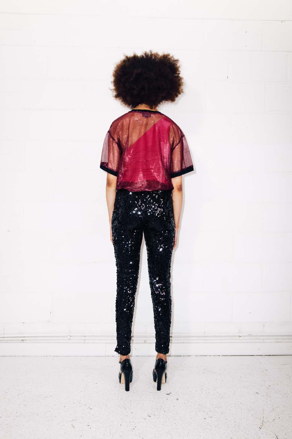 Woman wearing black sequin pants and red  mesh t-shirt as party outfit