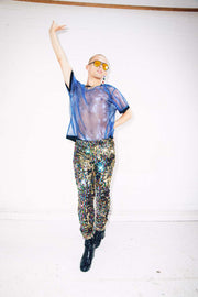 man wearing rainbow sequin pants and sheer blue mesh t shirt for pride outfit