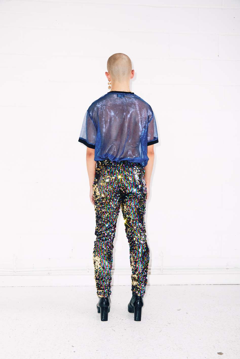 man wearing rainbow sequin pants and sheer blue top for rave outfit