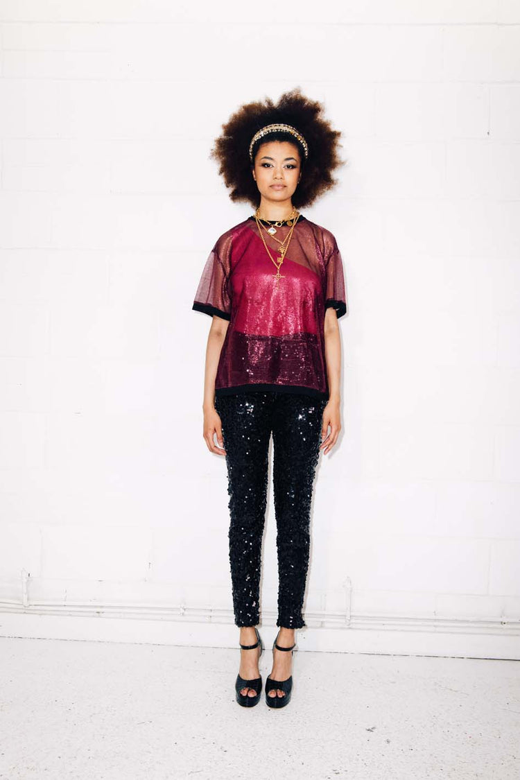 Woman wearing black sequin pants and red mesh t-shirt as party outfit